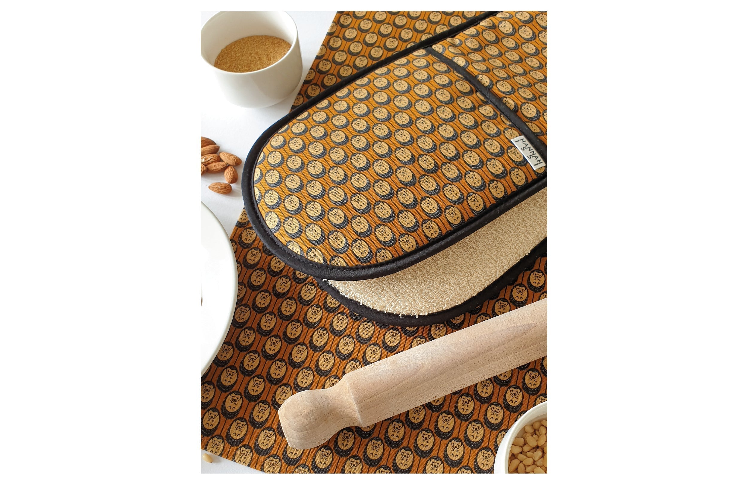 Double Oven Glove with matching tea towel in autumn colours hedgehog print- displayed on a table with a wooden rolling pin and cooking ingredients