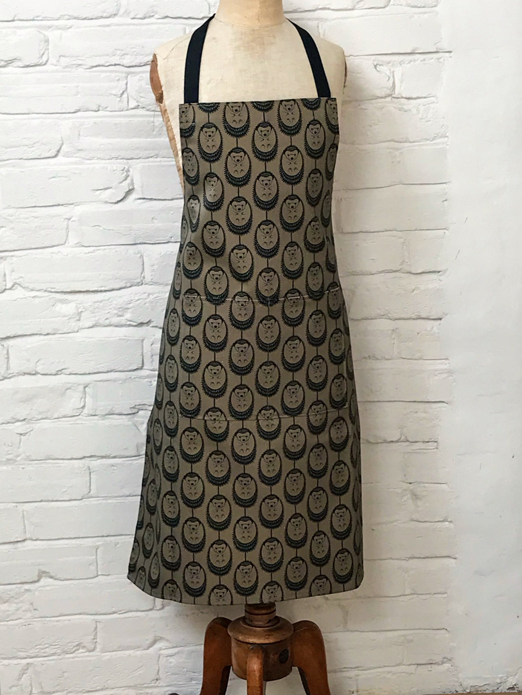 Organic cotton olive green hedgehog apron – designed by Hannah Issi and handmade in the UK. Stylish, sustainable kitchen accessory pictured on mannequin.