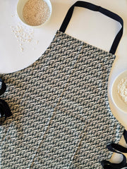 Organic cotton grey magpie apron – designed by Hannah Issi and handmade in the UK. Stylish, sustainable kitchen accessory - close-up picture on white background with cooking ingredients.