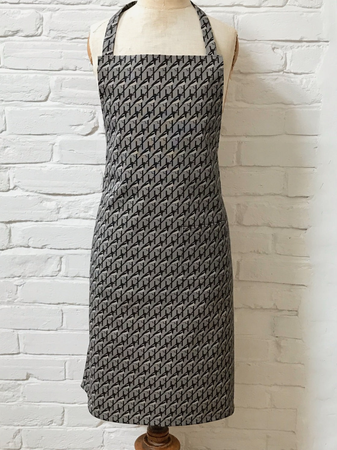 Organic cotton grey magpie apron – designed by Hannah Issi and handmade in the UK. Stylish, sustainable kitchen accessory - pictured on a mannequin.