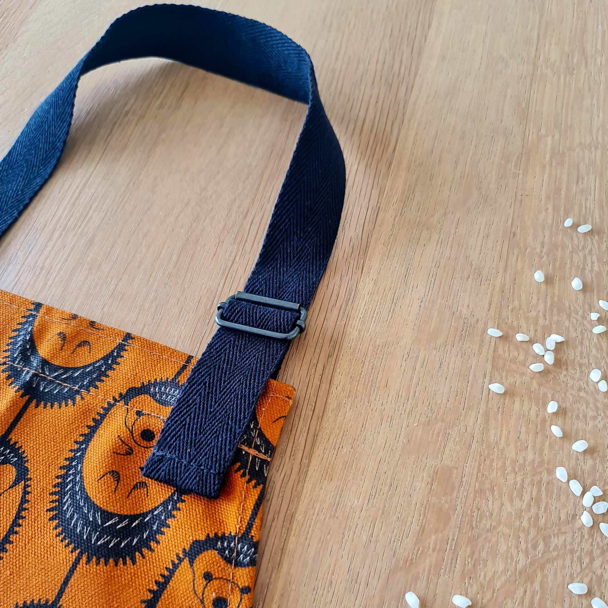 Organic cotton children’s terracotta hedgehog apron – handmade in the UK by Hannah Issi. Fun, sustainable kitchen accessory for kids. Close-up image showing adjustable neck strap.