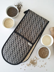 Organic cotton grey magpie double oven glove – handmade in the UK by Hannah Issi. Stylish, heat-safe kitchen accessory. Lifestyle image with white background and cooking ingredients. 