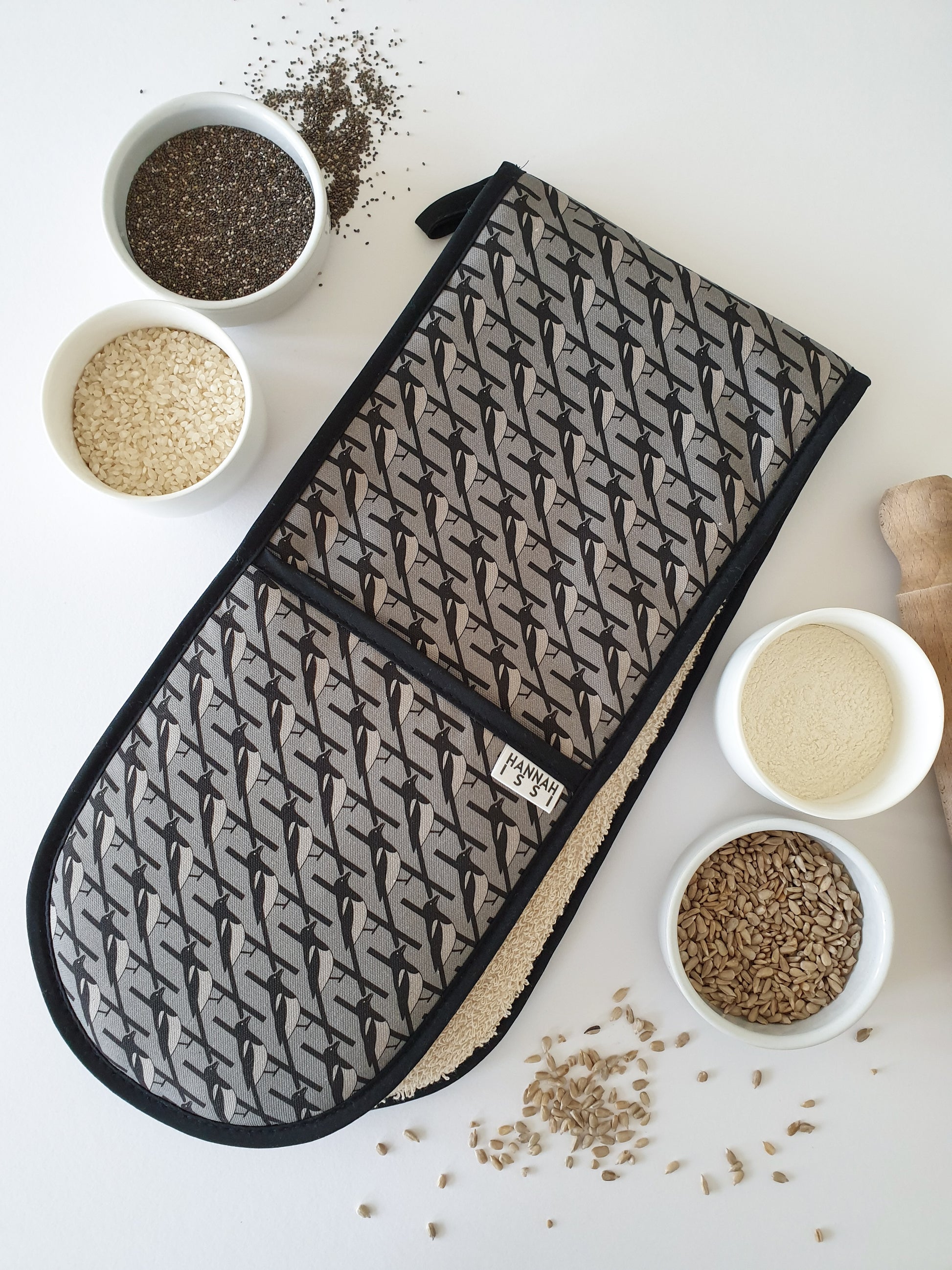 Organic cotton grey magpie double oven glove – handmade in the UK by Hannah Issi. Stylish, heat-safe kitchen accessory. Lifestyle image with white background and cooking ingredients. 