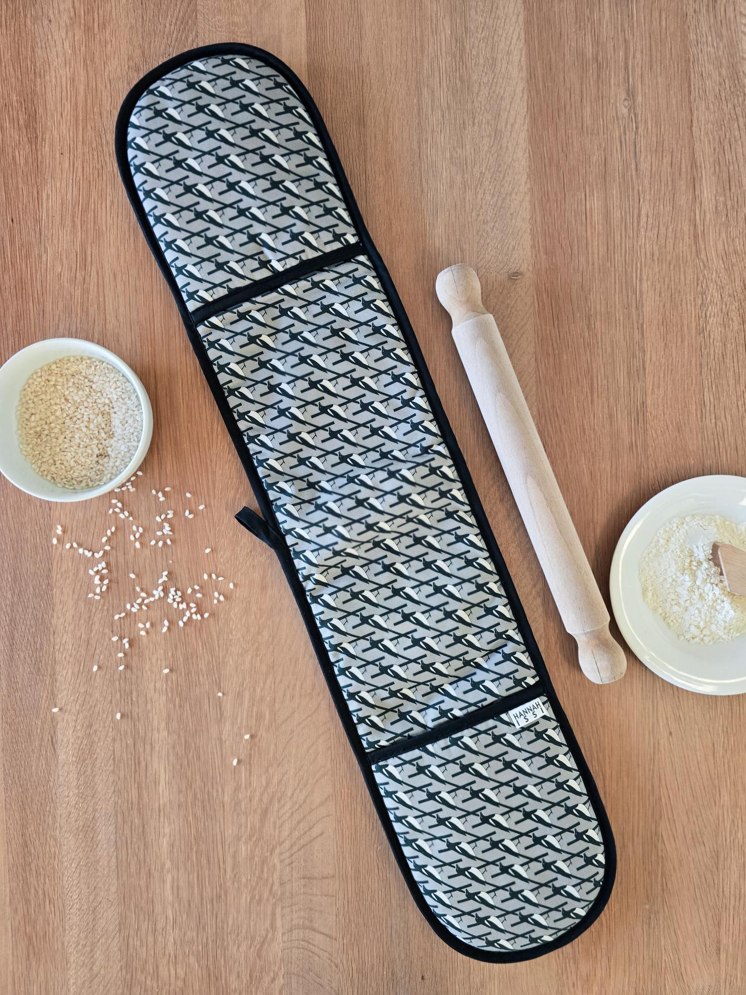 Organic cotton grey magpie double oven glove – handmade in the UK by Hannah Issi. Stylish, heat-safe kitchen accessory. Lifestyle image with wooden background.