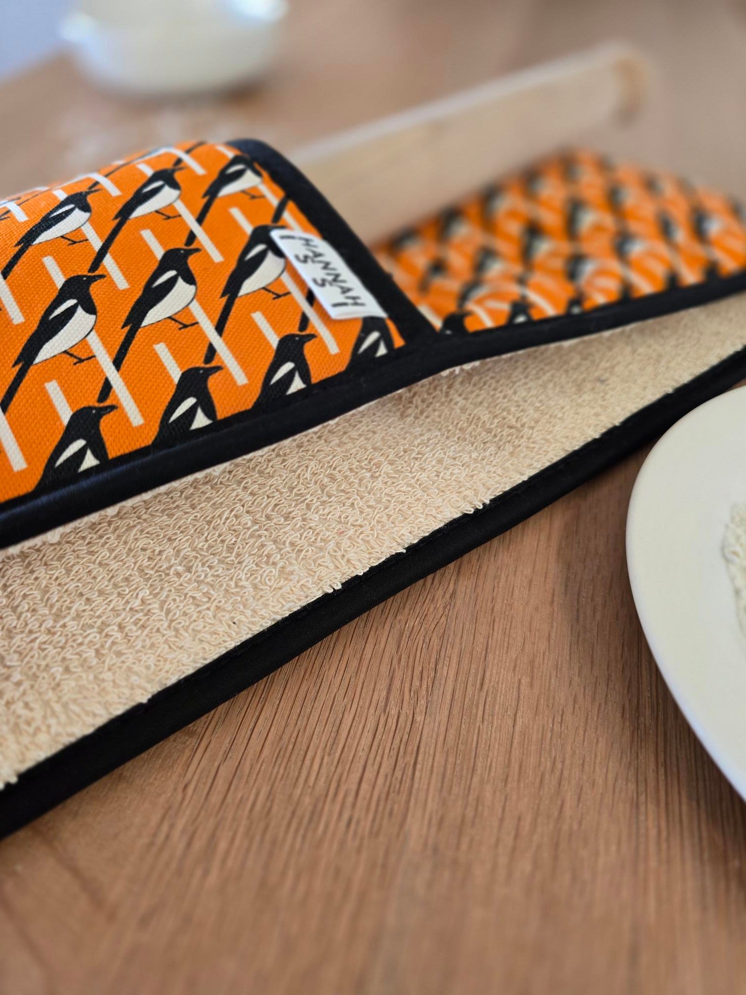 Organic cotton orange magpie double oven glove – handmade in the UK by Hannah Issi. Stylish, heat-safe kitchen accessory. Close-up lifestyle image showing print detail.
