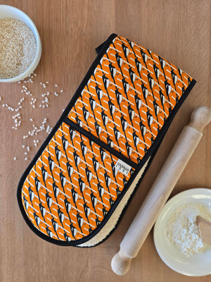 Organic cotton orange magpie double oven glove – handmade in the UK by Hannah Issi. Stylish, heat-safe kitchen accessory. Lifestyle image with wooden background and cooking ingredients.