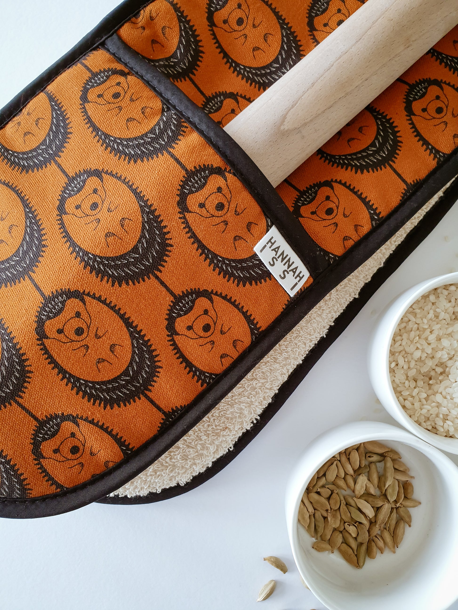 Organic cotton terracotta hedgehog double oven glove – handmade in the UK by Hannah Issi. Stylish, heat-safe kitchen accessory. Close-up lifestyle image with cooking ingredients.