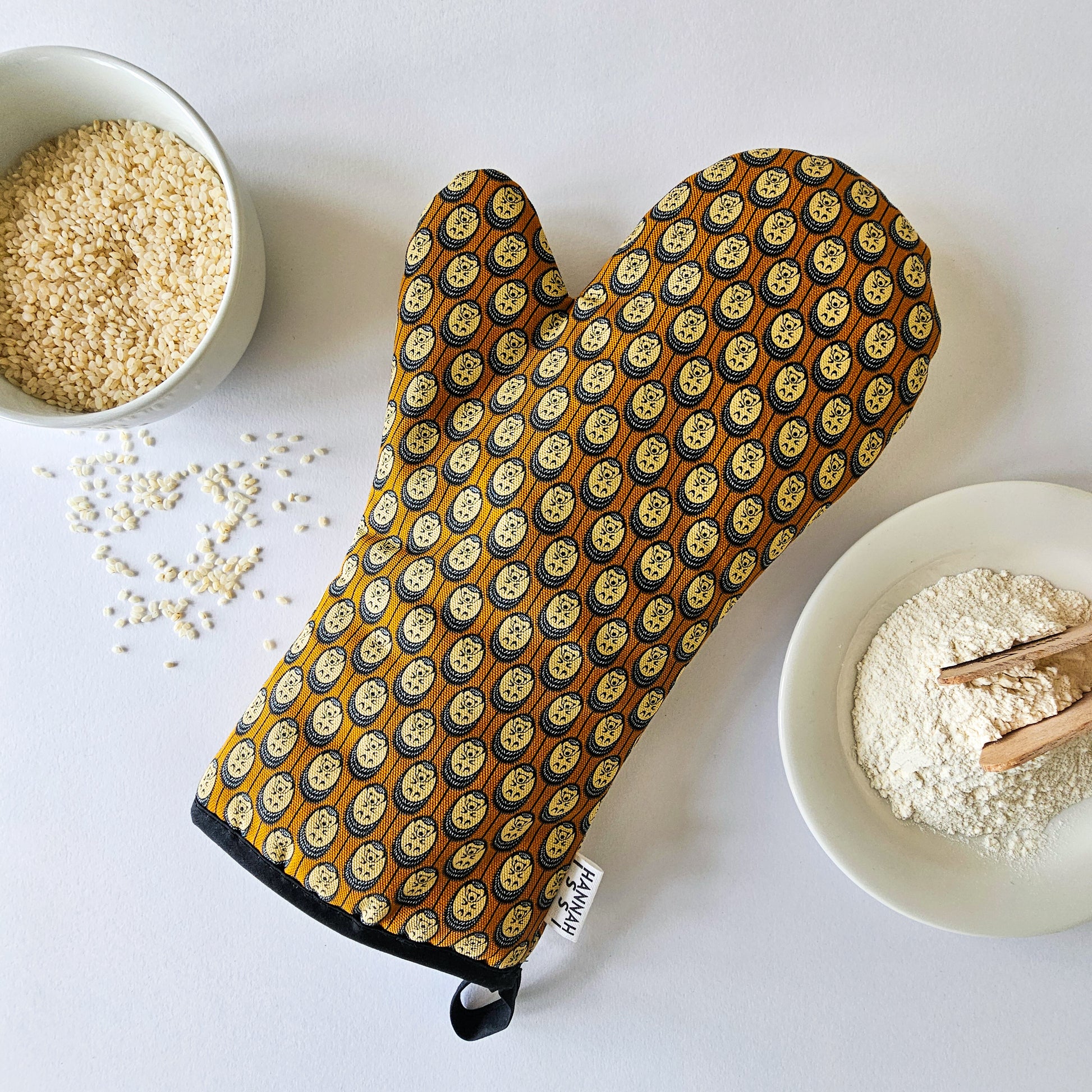 Organic cotton autumn hedgehog luxury oven glove – handmade in the UK by Hannah Issi. Stylish, heat-safe kitchen accessory. Lifestyle image with white background and cooking ingredients.