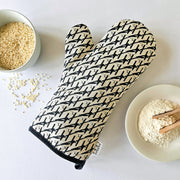 Organic cotton black & white magpie luxury oven glove – handmade in the UK by Hannah Issi. Stylish, heat-safe kitchen accessory. Lifestyle image with white background and cooking ingredients.