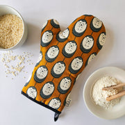 Organic cotton brown & white hedgehog luxury oven glove – handmade in the UK by Hannah Issi. Stylish, heat-safe kitchen accessory. Lifestyle image with white background and cooking ingredients.