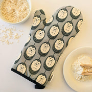 Organic cotton grey & white hedgehog luxury oven glove – handmade in the UK by Hannah Issi. Stylish, heat-safe kitchen accessory. Lifestyle image with white background and cooking ingredients.