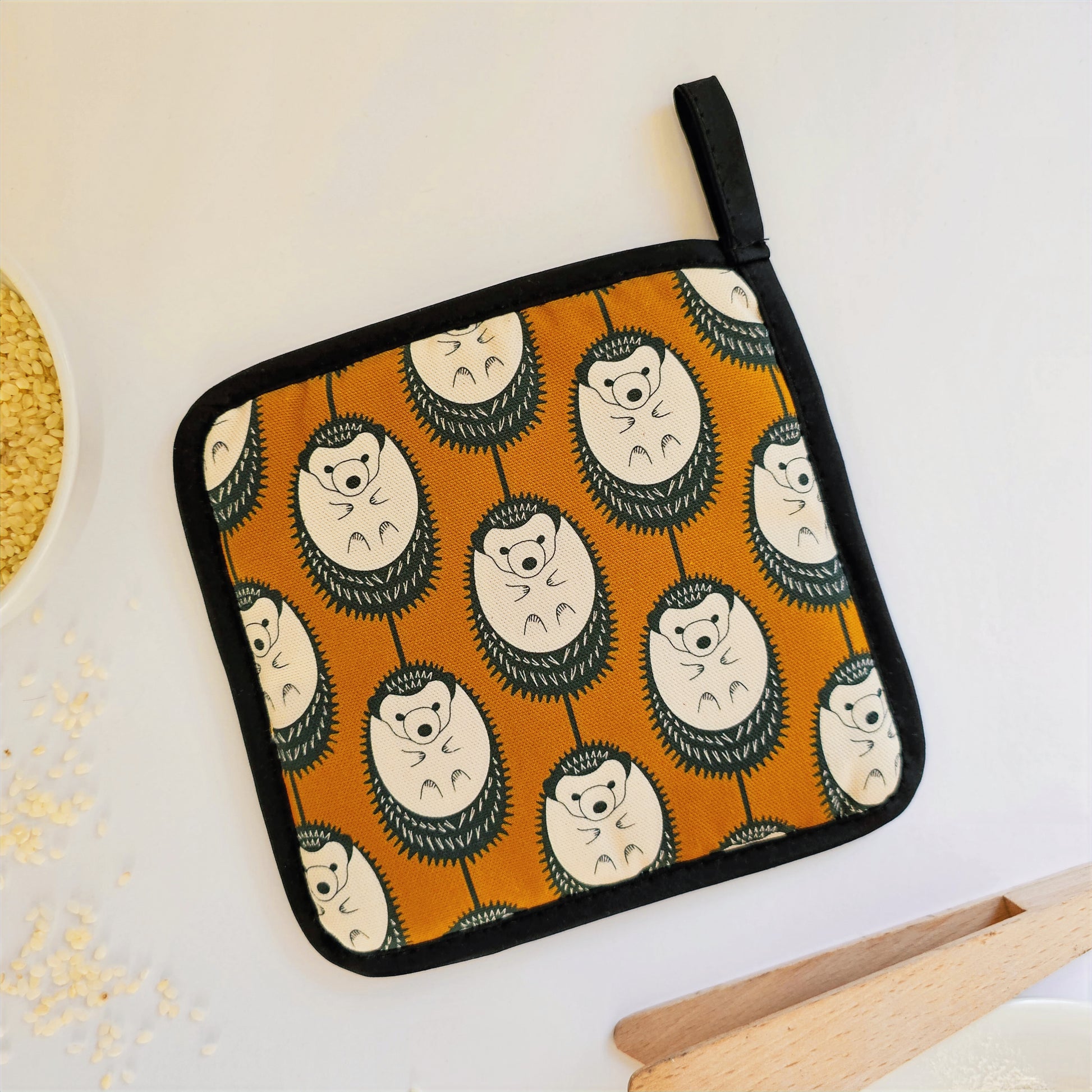 Organic cotton Brown & White Hedgehog pot grab – heat-safe kitchen handle cover by Hannah Issi, handmade in the UK. Stylish and functional. Reverse on white background with kitchen accessories. 
