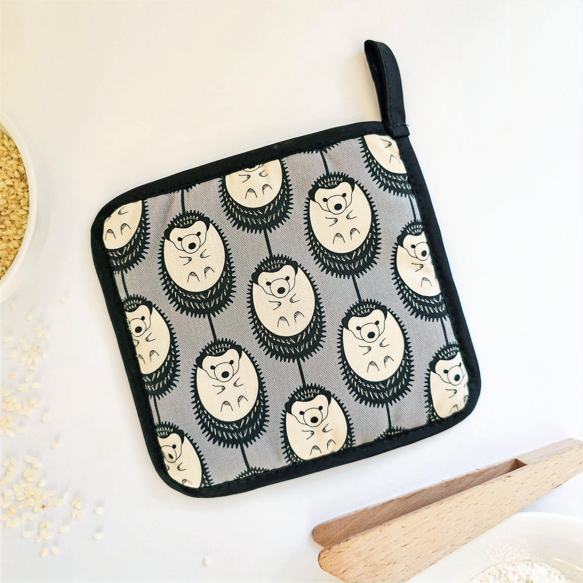 Organic cotton Grey & White Hedgehog pot grab – heat-safe kitchen handle cover by Hannah Issi, handmade in the UK. Stylish and functional. Reverse on white background with kitchen accessories. 