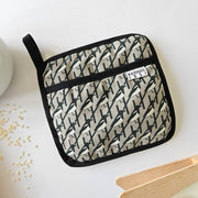 Organic cotton Grey Magpie pot grab – heat-safe kitchen handle cover by Hannah Issi, handmade in the UK. Stylish and functional. Image is on white background with kitchen accessories. 