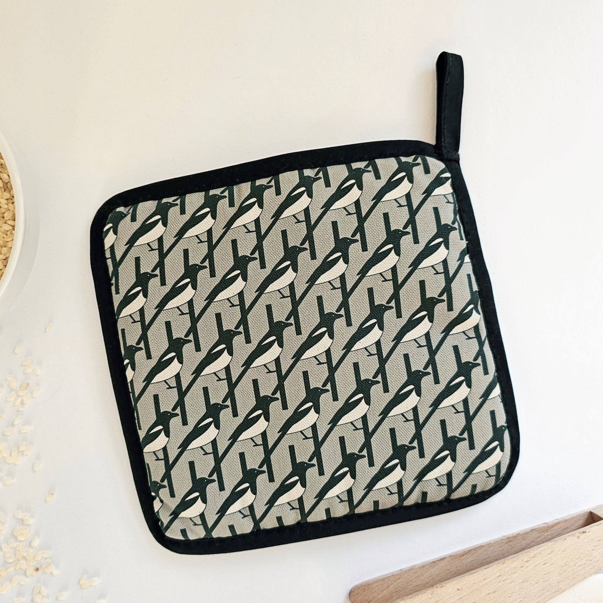 Organic cotton Grey Magpie pot grab – heat-safe kitchen handle cover by Hannah Issi, handmade in the UK. Stylish and functional. Image shows reverse on white background with kitchen accessories.