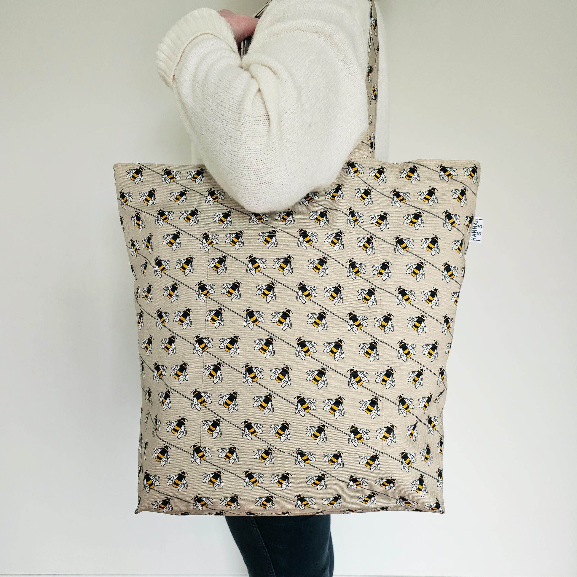 Organic cotton bee shoulder bag – handmade in the UK by Hannah Issi. Large, sustainable accessory for every day. Photo shows bag modelled on person's shoulder with white background.