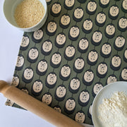 Organic cotton hedgehog tea towel in new green & white colour – designed by Hannah Issi and handmade in the UK. Sustainable, modern and eco-friendly kitchen textile. Lifestyle image showing close up of tea towel on white background with cooking ingredients and rolling pin.