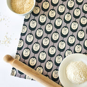 Organic cotton grey and white hedgehog tea towel – designed by Hannah Issi and handmade in the UK. Stylish, sustainable kitchen linen- shown on white background with wooden rolling pin and cooking ingredients. 